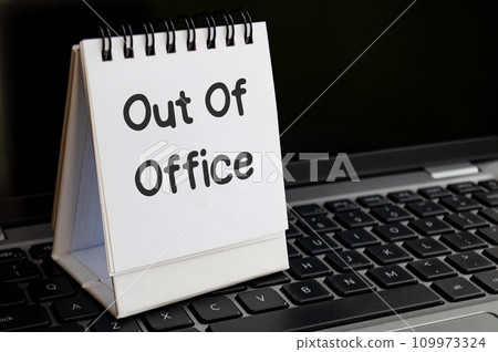 Out of office text on notepad with laptop background. Out of office concept. 109973324