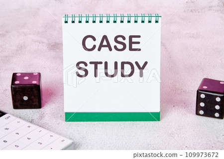 Case study text on a white notepad sheet next to dice on an abstract background 109973672