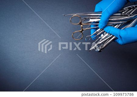 Hands in blue gloves holding metal dental equipment 109973786