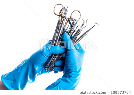 Hands in blue gloves holding dental equipment isolated Hands in blue gloves holding dental equipment isolated 109973794