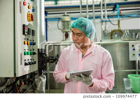 In a beverages factory a worker using a tablet oversees soda water filling while an engineer monitors machinery. Emphasizing quality control ensures high standards in bottle manufacturing. In a beverages factory a worker using a tablet oversees soda water filling while an engineer monitors machinery. Emphasizing quality control ensures high standards in bottle manufacturing. 109974477