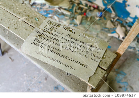 Torn cardboard with work schedule of House of Culture in abandoned building in resettled village of Pogonnoye in exclusion zone of Chernobyl, Belarus 109974637