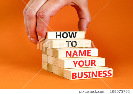 How to name your business symbol. Concept words How to name your business on wooden blocks. Beautiful orange table orange background. Businessman hand. How to name your business concept. Copy space. 109975793