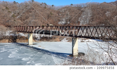 Limited express train crossing the Nakatetsu Bridge in the snowy scenery, Aizu Kinugawa Line, Yunishigawa Bridge 109975858