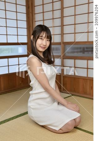 A young woman in a dress sitting in a Japanese-style room in an old folk house 109976204