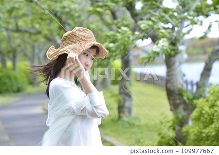 Fresh green park and young woman wearing a straw hat Fresh green park and young woman wearing a straw hat 109977667
