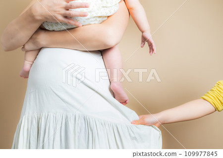 Hands of a woman holding a baby and an elementary school girl 109977845