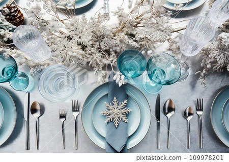 Christmas table setting with candles and crystal festive tableware and blue decor for Christmas celebration Christmas table setting with candles and crystal festive tableware and blue decor for Christmas celebration 109978201