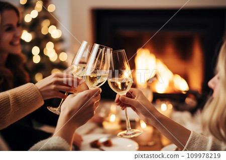 Happy friends having fun and toasting sparkling wine glasses close-up against burning fireplace background. Christmas celebration 109978219