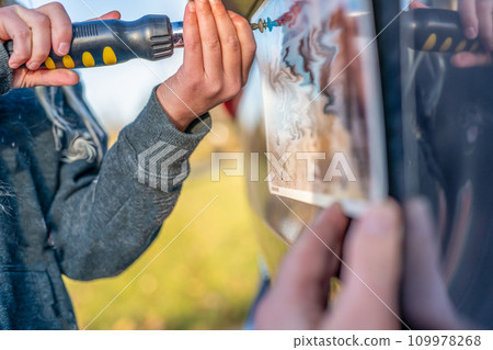 Using a screw driver to remove and replace a vehicle rear license plate.  109978268
