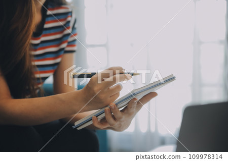 Asian Businesswoman Using laptop computer and working at office with calculator document on desk, doing planning analyzing the financial report, business plan investment, finance analysis concept. 109978314