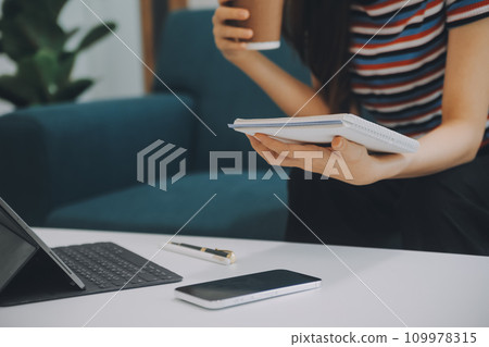 Asian Businesswoman Using laptop computer and working at office with calculator document on desk, doing planning analyzing the financial report, business plan investment, finance analysis concept. 109978315
