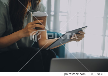 Asian Businesswoman Using laptop computer and working at office with calculator document on desk, doing planning analyzing the financial report, business plan investment, finance analysis concept. 109978318