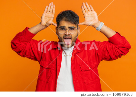 Displeased funny bully Indian man showing tongue making silly faces, fooling around, joking, teasing 109979163