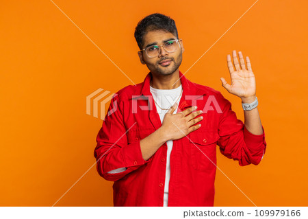 Indian man raising hand to take oath, promising to be honest and to tell truth keeping hand on chest Indian man raising hand to take oath, promising to be honest and to tell truth keeping hand on chest 109979166