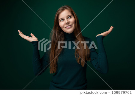 Caucasian young woman wearing a green turtleneck on a dark background with copy space 109979761