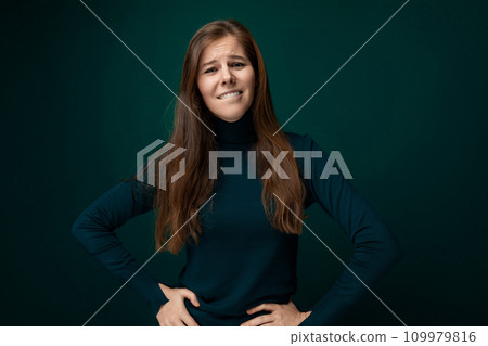 Caucasian young woman wearing a green turtleneck on a dark background with copy space 109979816