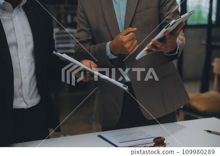 Business and lawyers discussing contract papers with brass scale on desk in office. Law, legal services, advice, justice and law concept picture with film grain effect Business and lawyers discussing contract papers with brass scale on desk in office. Law, legal services, advice, justice and law concept picture with film grain effect 109980289