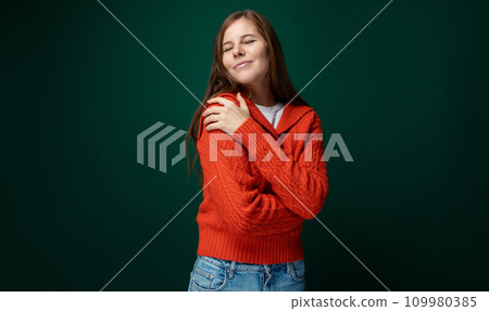 Smiling young woman with brown straight hair wearing a red sweater on a green background with copy Smiling young woman with brown straight hair wearing a red sweater on a green background with copy 109980385
