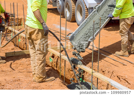 Using concrete vibrator construction worker compacts concrete into trenches for foundation of house Using concrete vibrator construction worker compacts concrete into trenches for foundation of house 109980957
