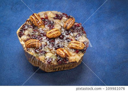 holiday rum cake with pecans, pineapple, dried cherries and cranberries against blue art paper 109981076