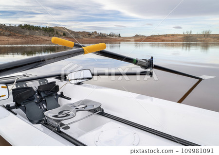Detail of a coastal rowing shell with sculling oars, footstretcher, sliding seat and mirrors on a shore of Horsetooth Reservoir in northern Colorado Detail of a coastal rowing shell with sculling oars, footstretcher, sliding seat and mirrors on a shore of Horsetooth Reservoir in northern Colorado 109981091