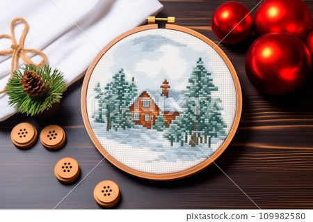 A framed embroidered christmas card with ornaments and candles on wooden table. Winter background with pine twigs 109982580