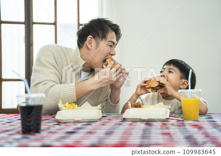 father and son eating hamburgers father and son eating hamburgers 109983645