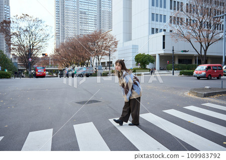 A woman crossing a pedestrian crossing A woman crossing a pedestrian crossing 109983792