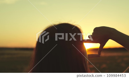 Tourist with hands folded in form of objective frame looks through fingers at sun 109984453