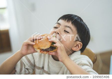 Boy eating hamburger 109985406