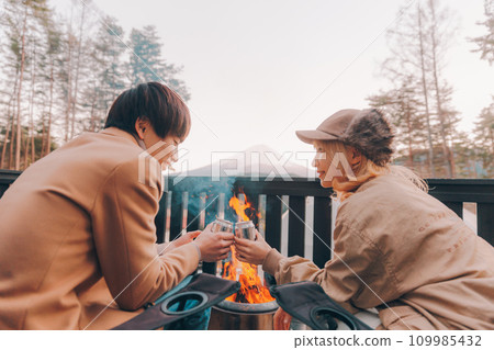 Couple toasting over a bonfire at a campsite Couple toasting over a bonfire at a campsite 109985432
