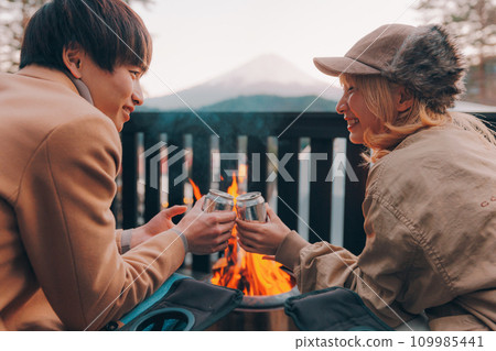 Couple toasting over a bonfire at a campsite 109985441