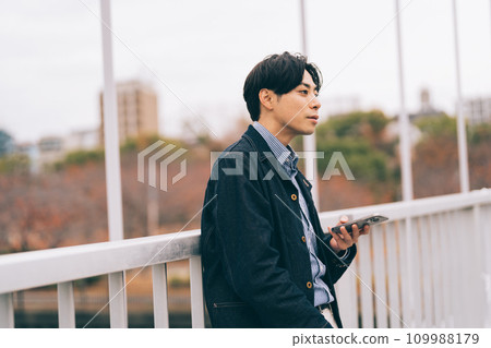 一名男子在橋上看著他的智慧型手機 109988179