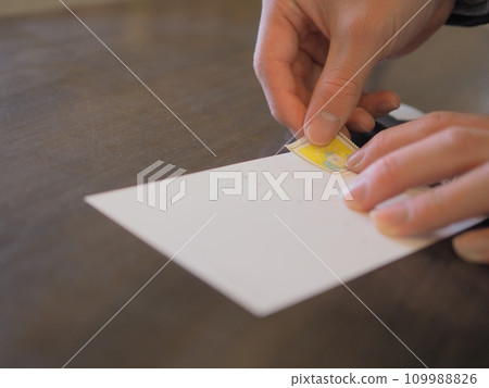 男人的手在明信片上貼郵票 男人的手在明信片上貼郵票 109988826