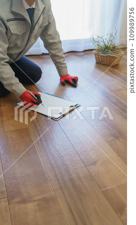 A man in work clothes checking and inspecting the flooring A man in work clothes checking and inspecting the flooring 109989756