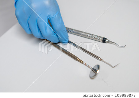 Close up dentist hand takes dental hook from the table. 109989872