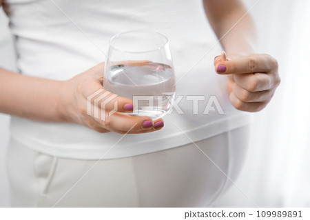Pregnant woman takes pills during pregnancy. Illnesses, lack of vitamins concept  109989891