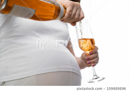 Irresponsible pregnant woman pours wine into the glass. Alcohol during pregnancy 109989896