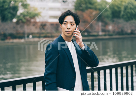 A man talking on the phone by the river 109989902