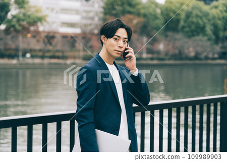 A man talking on the phone by the river 109989903