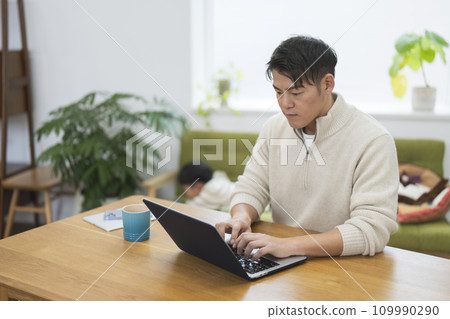 一名 30 多歲的男子在家工作,同時照顧孩子 一名 30 多歲的男子在家工作,同時照顧孩子 109990290