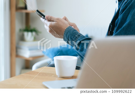 在家操作智慧型手機的中年男子 在家操作智慧型手機的中年男子 109992622