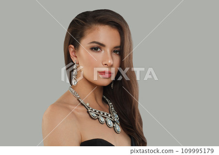 Beautiful glamorous woman jewelry model with diamonds posing on gray background Beautiful glamorous woman jewelry model with diamonds posing on gray background 109995179