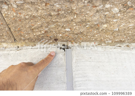Hand pointing at the boundary between concrete joint and block wall 109996389