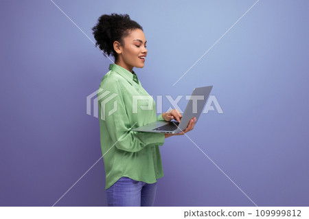 successful young bright latin woman dressed in a green blouse works remotely with a laptop successful young bright latin woman dressed in a green blouse works remotely with a laptop 109999812