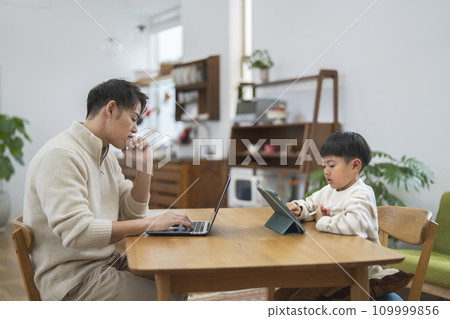 Image of a boy operating a tablet PC and his father working from home 109999856