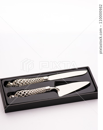 Wedding cake is set next to stainless steel utensil serving set for bride and groom to cut a slice of cake. Wedding cake is set next to stainless steel utensil serving set for bride and groom to cut a slice of cake. 110000982