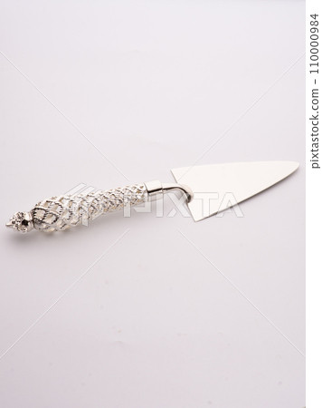 Wedding cake is set next to stainless steel utensil serving set for bride and groom to cut a slice of cake. Wedding cake is set next to stainless steel utensil serving set for bride and groom to cut a slice of cake. 110000984