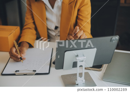 Startup SME small business entrepreneur of freelance Asian woman using a laptop with box Cheerful success happy Asian woman her hand lifts up online marketing packaging and delivery SME idea concept 110002289